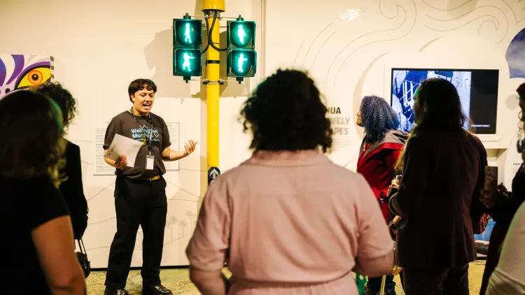 Curator talking to a crowd next to a traffic light display