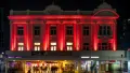 Nighttime photograph of the front of the Wellington Opera House, red lights illuminate the decorative columns.