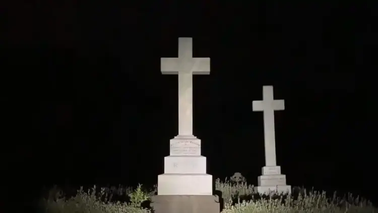 Two white tombstone of crosses, black background