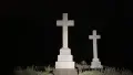 Two white tombstone of crosses, black background