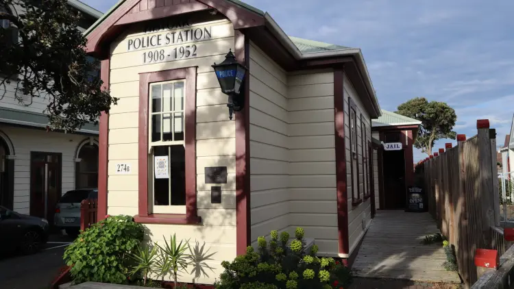 Colour photograph of a yellow and burgandy police station with text reading: "Police Station 1908-1952"
