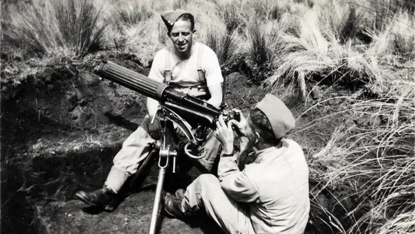 Black and white photograph of two men looking through a telescope in a field