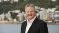 Man standing in front of Wellington harbour, smiling