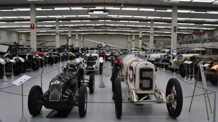 A large warehouse full of cards of various ages, backed by three aeroplanes.