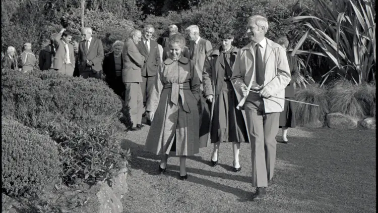 Black and white photograph of people walking through a garden