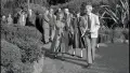 Black and white photograph of people walking through a garden