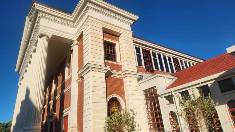 A photograph of the Sacred Heart Cathedral, a red and white stone and brick building with Roman columns at the entrance.