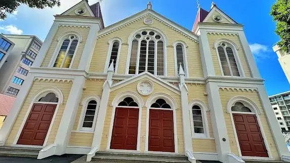 Exterior shot of white and cream church with red doors