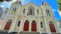 Exterior shot of white and cream church with red doors