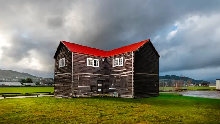 Two storey timber building with red roof in field