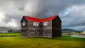 Two storey timber building with red roof in field