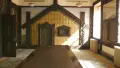 Interior shot of a side lit room with a facade of a Māori whare at the end of a table