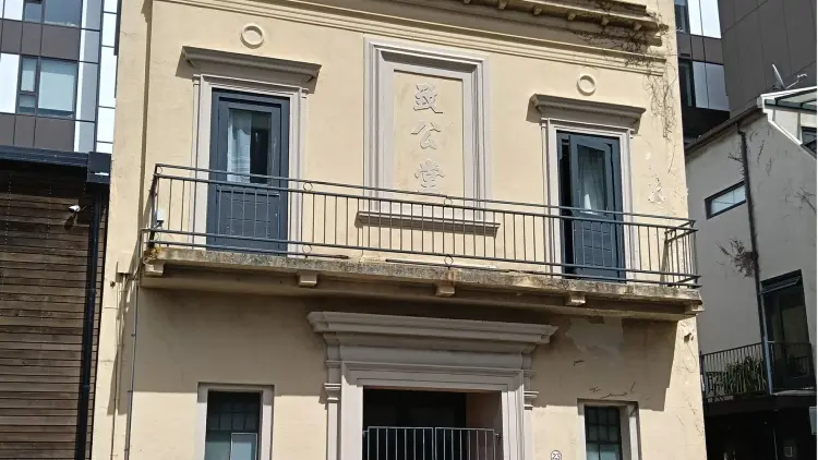 Soft yellow coloured colonial concrete building with metal rail balcony and gated entrance