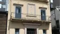 Soft yellow coloured colonial concrete building with metal rail balcony and gated entrance