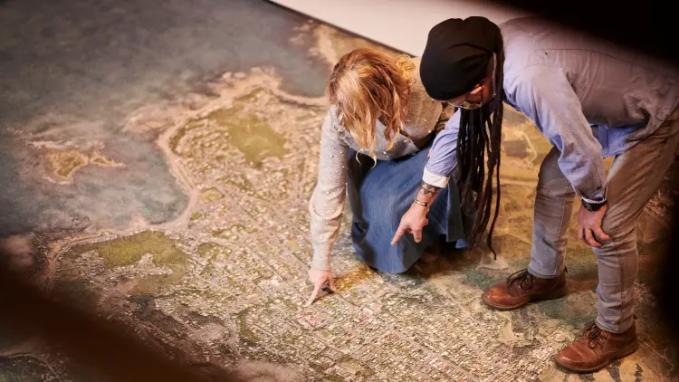 Two people pointing at a floor map