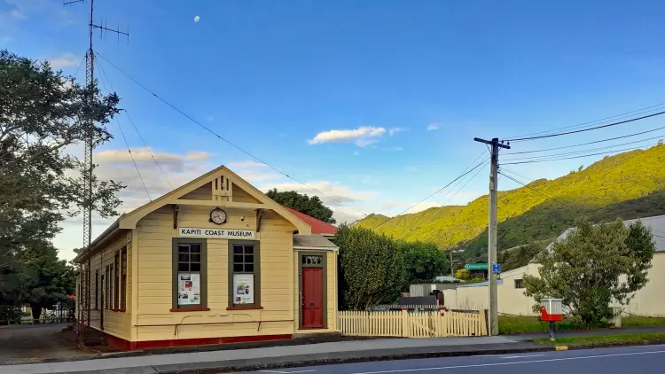 Exterior shot of an old building, yellow and red, with a sign reading "Kāpiti Coast MUSEUM"