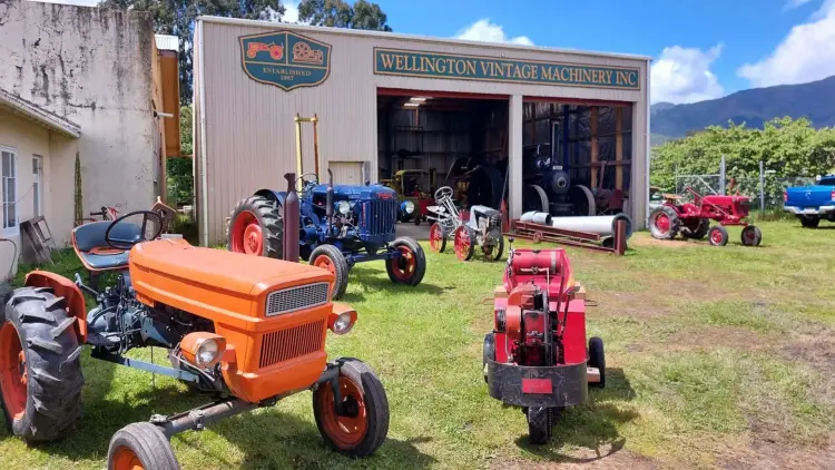 Photograph of the Wellington Vintage Machinery Inc Shead with brightly painted vintage tractors parked on the grass out front.