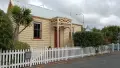 Yellow painted and white roof house behind a white picket fence