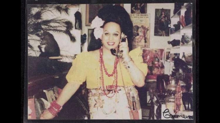 Carmen Rupe in a decorated room holding a vintage phone