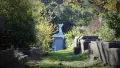 Graveyard with green grass and trees, angel stone statue in the background