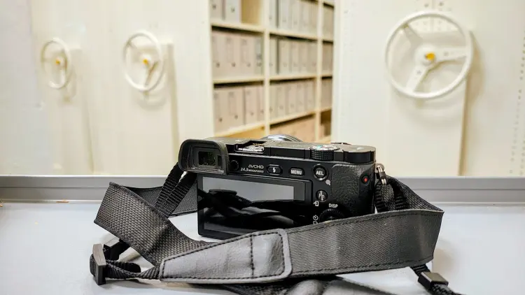 Photo of digital camera next to archive shelves
