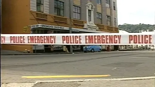 White police emergency tape with red text in foreground, brick building