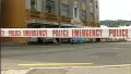 White police emergency tape with red text in foreground, brick building