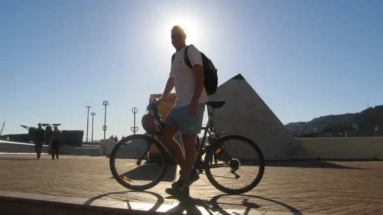 Outdoors hoft of a man standing by a bicycle