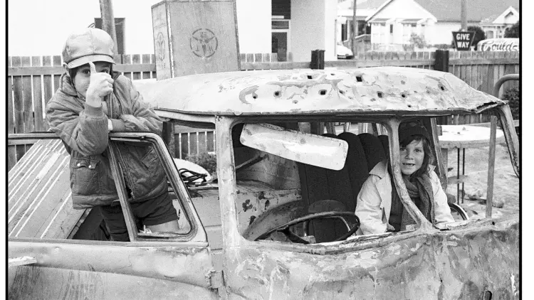 Black and white photograph of two children inside an old car