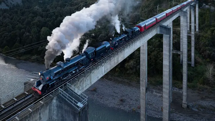 Steam train travelling over concrete bridge