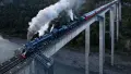 Steam train travelling over concrete bridge