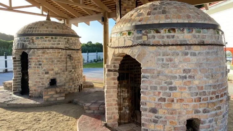 Two historic brick kilns under a wooden verandah