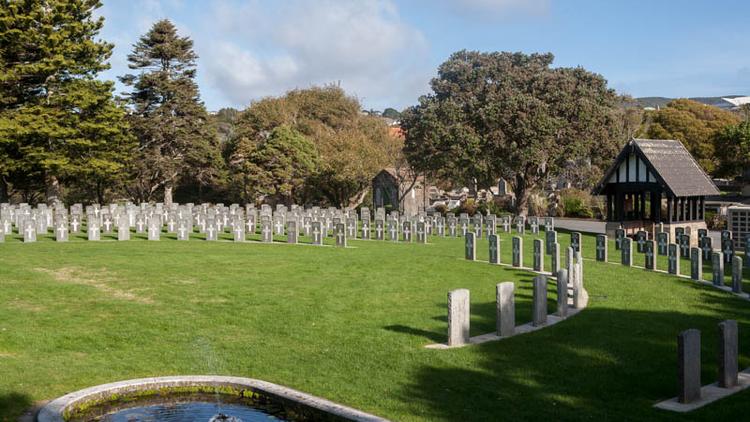 Daylight photo of Karori Cemetery. Concentric grave circles with a pond in the foreground.