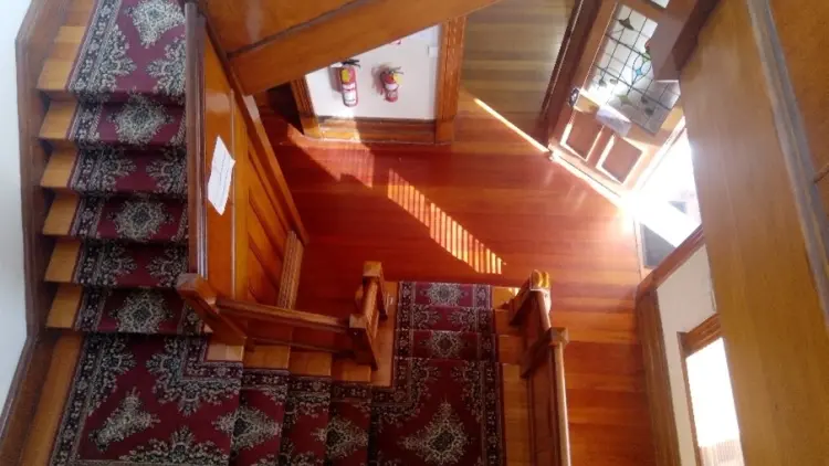 Looking down on a native timber staircase with a red rug