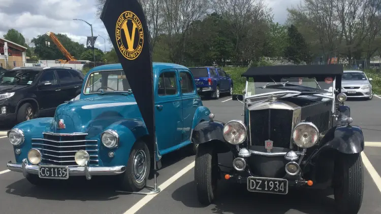 A photograph of two vintage vehicles, one blue one black