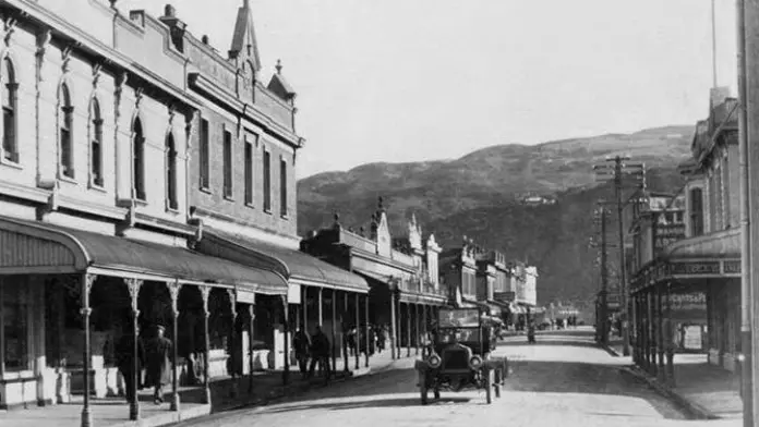 Black and white photo of a stree with a vintage car