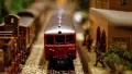 Red toy train and figures standing on a railway platform