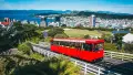 Red cable car with park and city harbour behind