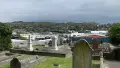View of graveyard of green lawn and tombstones, city in the background and grey skies