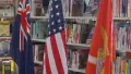 Three flags in front of a shelf of books
