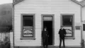 Historic photo of two people outside a store