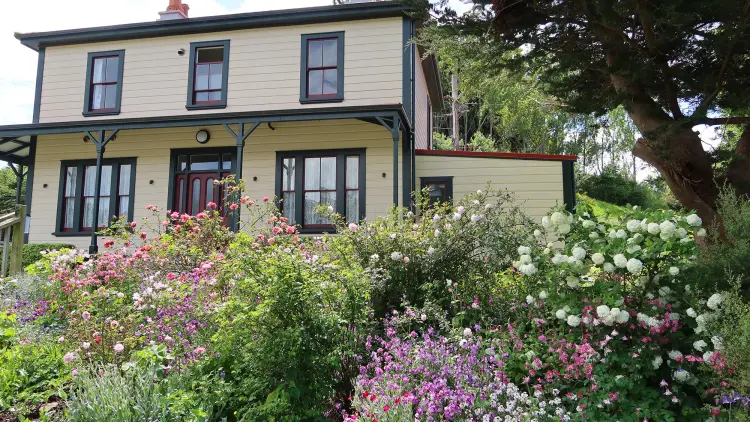 Colour photograph of the Half Way house, a yellow house surrounded by colourful flowers and garden