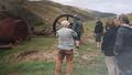 Photo of a group of people listening to a talk with hills in the background with some of the machinery laying on the grass. 