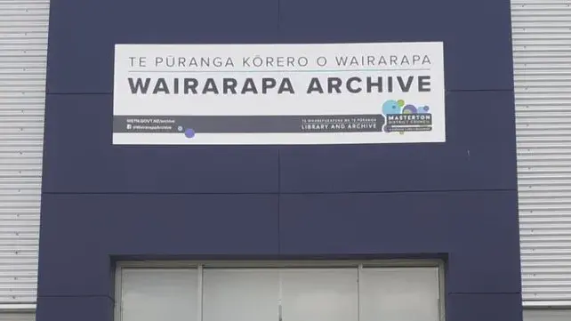 Photograph of the front of a navy and grey building with a sign for the Wairarapa Archive above the glass doors