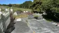 Graveyard with white picket fence on left and green trees on the right