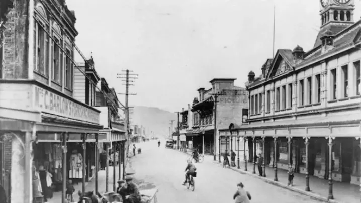 Black and white photograph of an old street with people on bicycles
