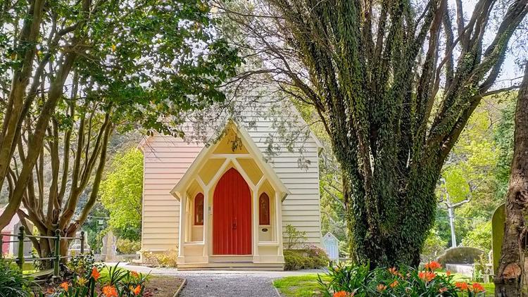 Exterior of church, cream in colour with red doors