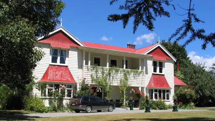 A photograph of Llandaff Homestead, a white and red building surrounded by trees. 