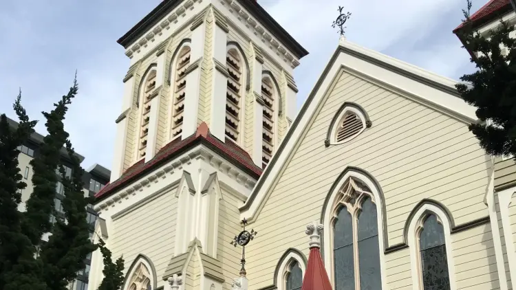 The front of a large wooden cream and red church in the daytime.