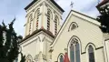 The front of a large wooden cream and red church in the daytime.